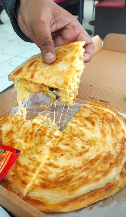 Cheesy special pizza paratha with a long cheese pull