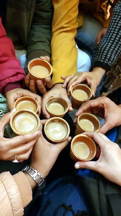 Friends holding cups of chai together in a warm huddle at Quetta City Chai Paratha