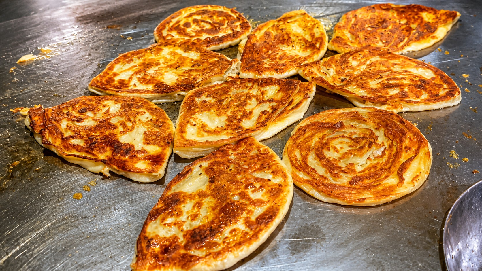 Fresh paratha cooking on a hot tawa over open flame